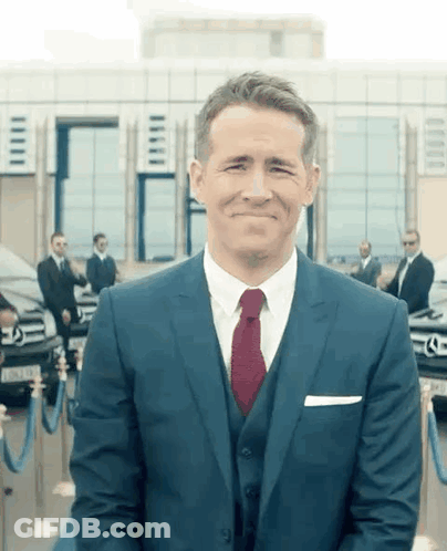 Man In Suit And Tie Smiling In Front Of Building GIF