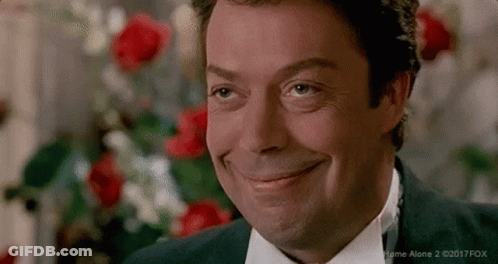 Man In Suit And Tie Smiling In Front Of Red Roses GIF