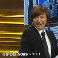 Man In Suit And Tie Smiling In Front Of Staircase GIF