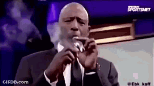 Man In Suit And Tie Smoking Cigarette And Speaking Into Microphone GIF