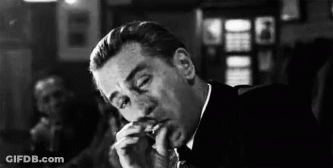 Man In Suit And Tie Smoking Cigarette In Bar GIF