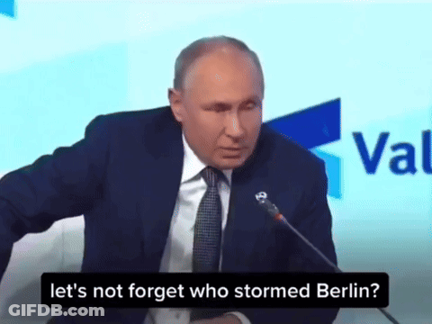 Man In Suit And Tie Speaking Into Microphone Saying Let's Not Forget Who Stormed Berlin GIF