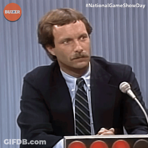 Man In Suit And Tie Speaking Into Microphone With Buzzr GIF