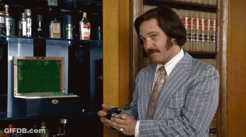Man In Suit And Tie Standing Before Bookshelf GIF