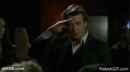 Man In Suit And Tie Standing Before Crowd In Dark Room GIF