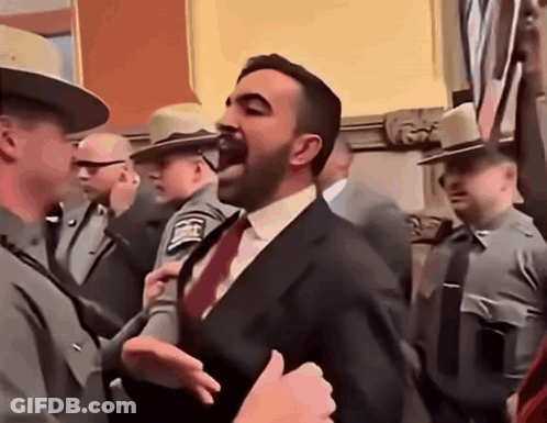 Man In Suit And Tie Standing Before Police Officers GIF