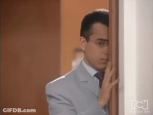 Man In Suit And Tie Standing Behind Door GIF