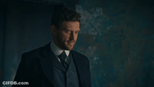 Man In Suit And Tie Standing In Dark Room GIF