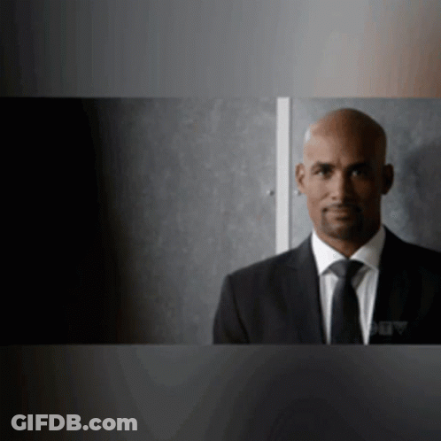 Man In Suit And Tie Standing In Dark Room GIF