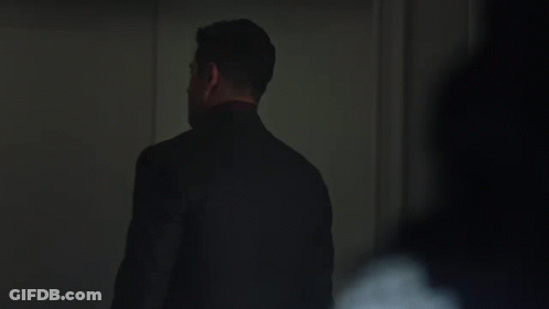 Man In Suit And Tie Standing In Dark GIF