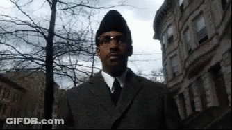 Man In Suit And Tie Standing In Front Of Buildings GIF