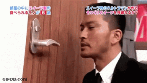 Man In Suit And Tie Standing In Front Of Door With Japanese Writing GIF