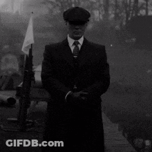 Man In Suit And Tie Standing In Front Of Flag And Gun GIF