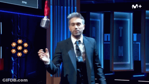 Man In Suit And Tie Standing In Front Of M+ Sign GIF