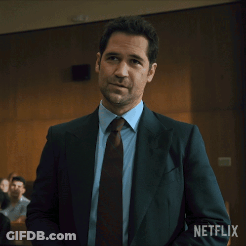 Man In Suit And Tie Standing In Front Of Netflix Sign GIF
