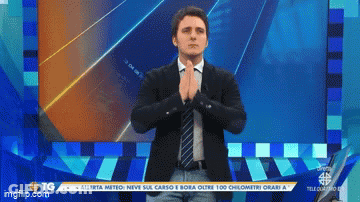 Man In Suit And Tie Standing In Front Of Screen Saying TG GIF