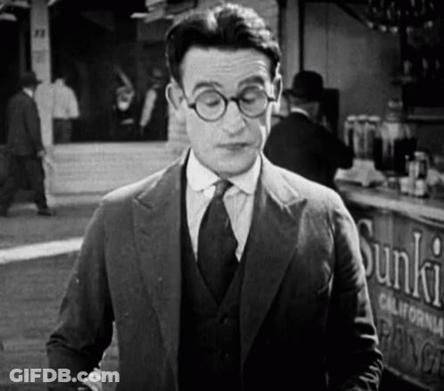 Man In Suit And Tie Standing In Front Of Sunkist Sign GIF