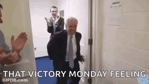 Man In Suit And Tie Standing In Hallway With Other Men GIF