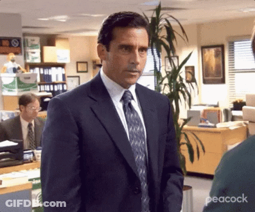 Man In Suit And Tie Standing In Office With Plant GIF