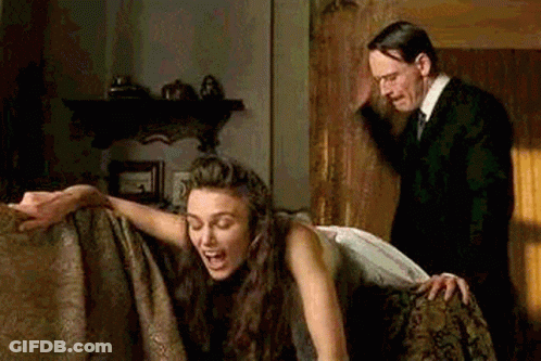Man In Suit And Tie Standing Next To Woman On Couch GIF