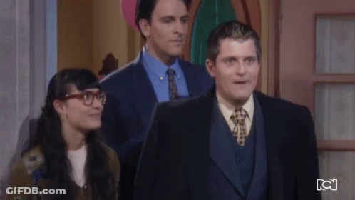 Man In Suit And Tie Standing Next To Woman With Glasses GIF