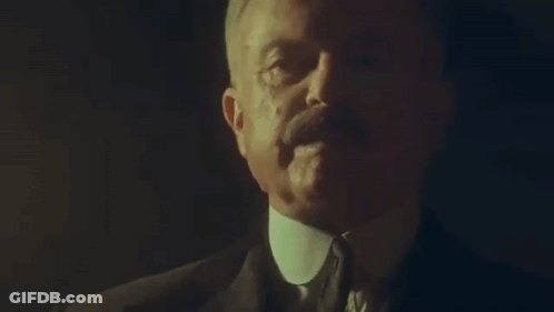 Man In Suit And Tie Talking In Dark Room GIF