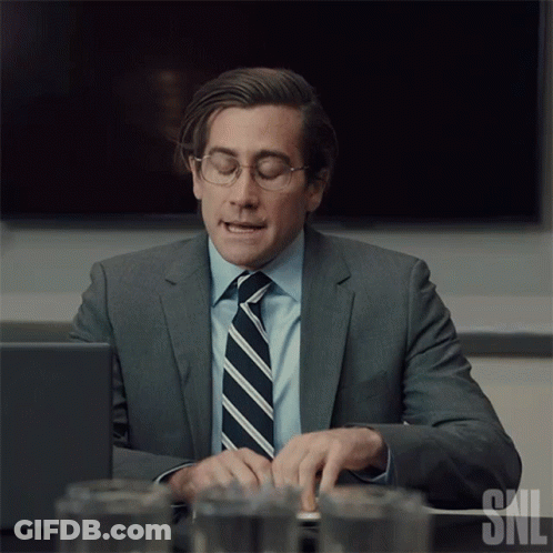 Man In Suit And Tie Typing On Laptop With SNL Logo GIF