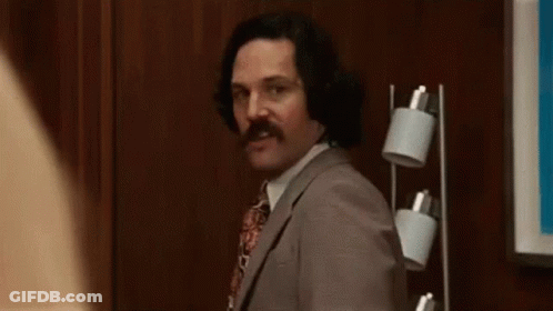 Man In Suit And Tie Waving Near Lamp GIF