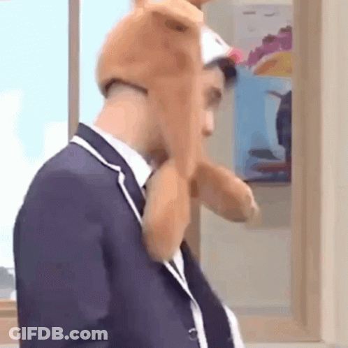 Man In Suit And Tie Wearing Stuffed Animal Hat GIF