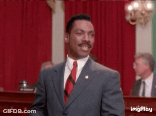Man In Suit And Tie With Arms In The Air In Front Of Crowd GIF