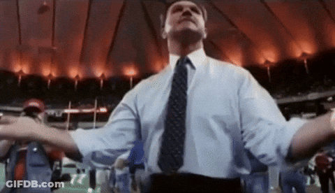 Man In Suit And Tie With Arms Outstretched In Stadium GIF