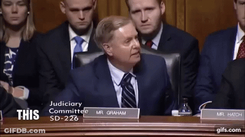 Man In Suit And Tie With Sign Saying This GIF