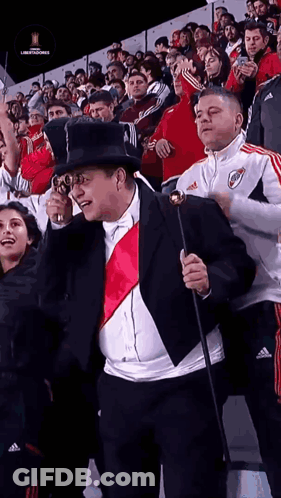 Man In Suit And Top Hat Holding Cane Before Crowd GIF