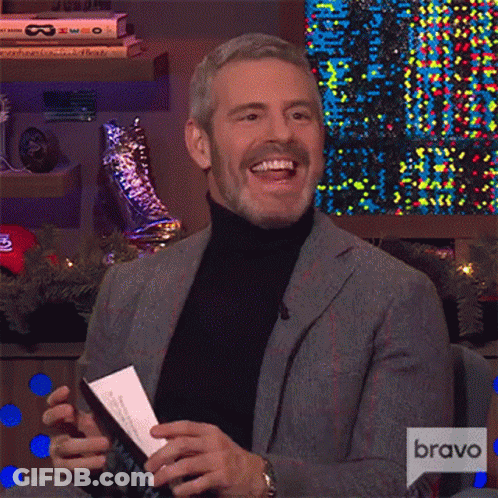 Man In Suit And Turtleneck Laughing Holding Paper GIF