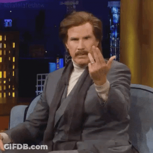 Man In Suit And Turtleneck Sitting On Couch Giving Middle Finger GIF