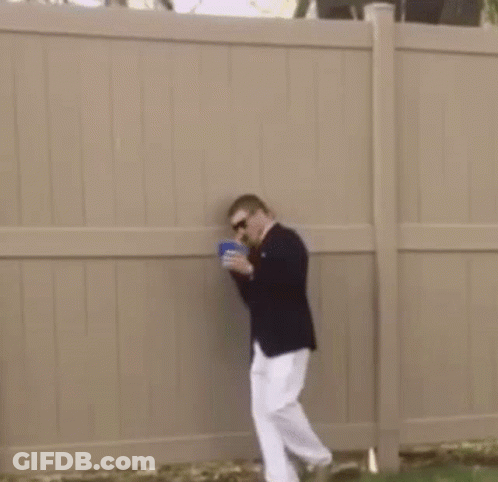 Man In Suit And White Pants Standing In Grass With Cup GIF