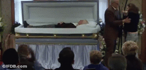 Man In Suit And Woman Beside Coffin GIF