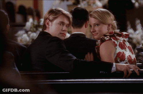 Man In Suit And Woman In Floral Dress Sitting On Bench GIF
