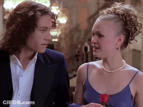 Man In Suit And Woman In Pearl Necklace Looking At Each Other GIF