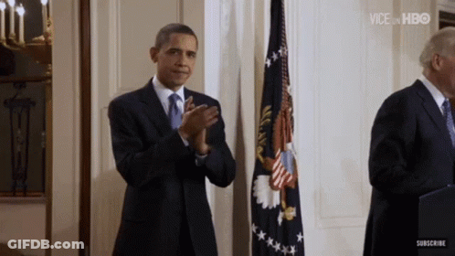 Man In Suit Applauding In Front Of Flag GIF