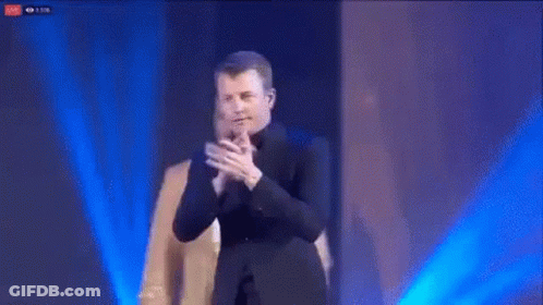 Man In Suit Applauding With Another Man Behind GIF