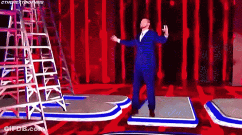 Man In Suit Arms Outstretched On Red Stage GIF
