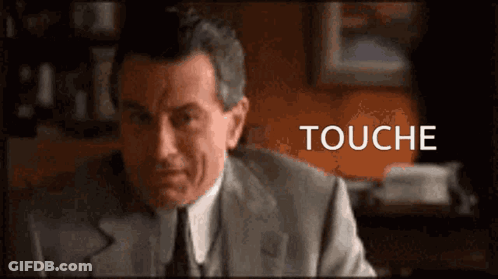 Man In Suit At Desk Saying Touché GIF