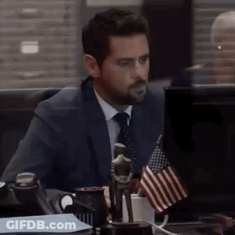 Man In Suit At Desk With American Flag GIF