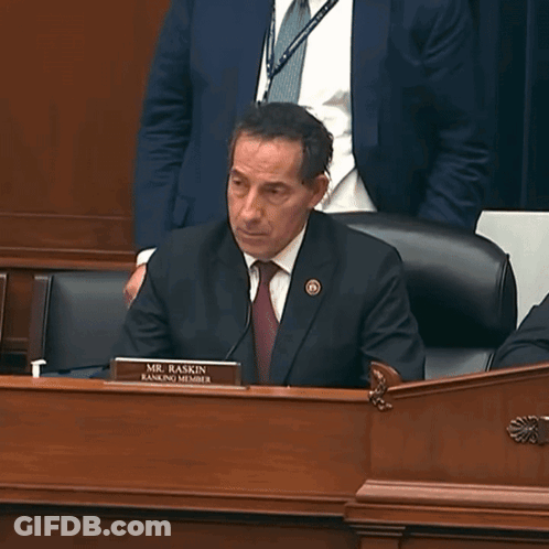 Man In Suit At Desk With Mr. Raskin Name Tag GIF