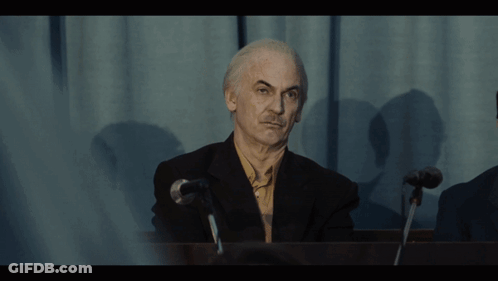 Man In Suit At Microphone In Dark Room GIF