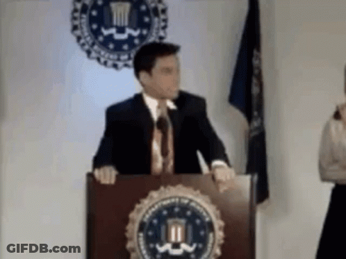 Man In Suit At Podium With DOJ Seal GIF