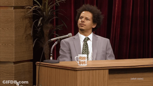 Man In Suit At Podium With Ice Cream Mug GIF