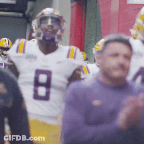 Man In Suit At Podium With LSU Sign GIF