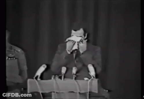 Man In Suit At Podium With Microphones GIF